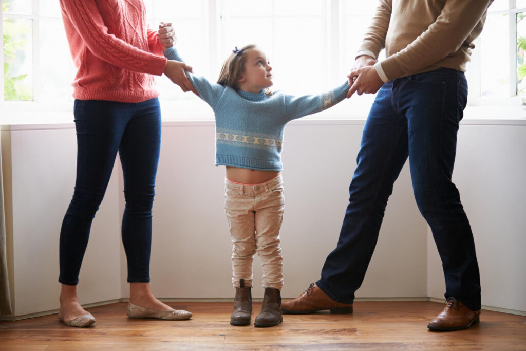 A woman holds a childs hands